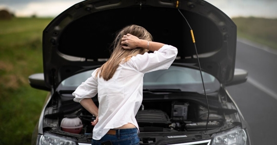 woman looking in open hood of car