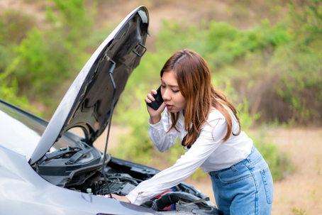 woman on the phone while trying to fix her car