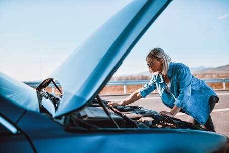 woman fixing car on side of the road