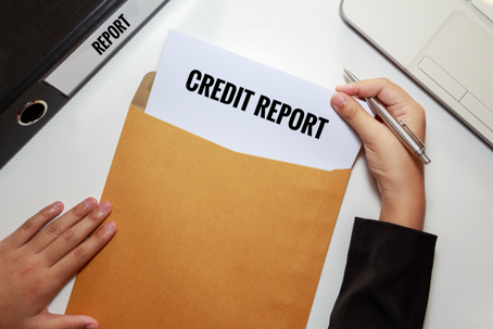 Cropped Hands Removing Credit Report From Envelope At Table